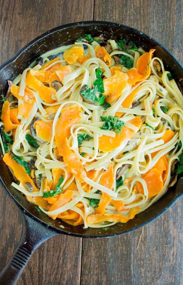 Overhead shot of Healthy Kale Squash Mushroom Pasta in a creamy sauce served in a black skillet