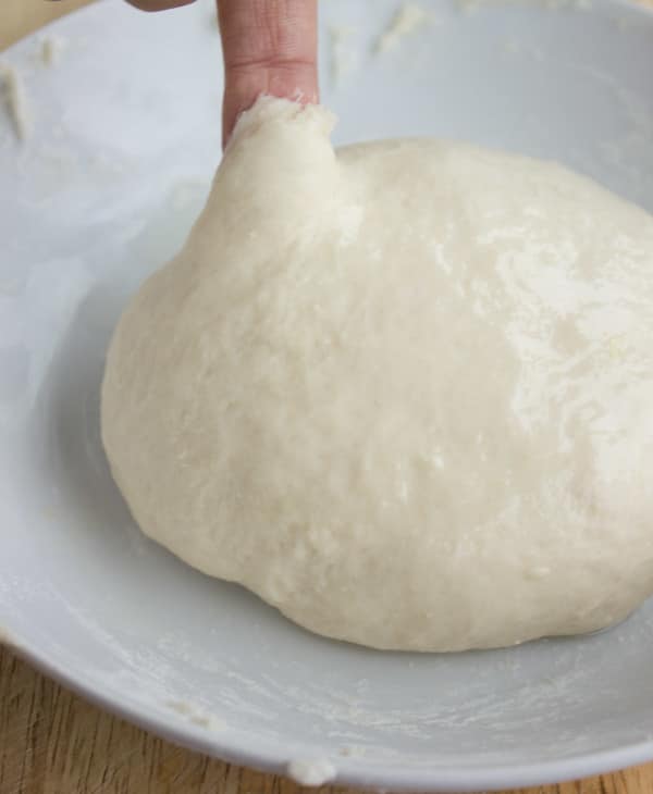 yeasted soft burger bun dough dough after kneading in a white bowl