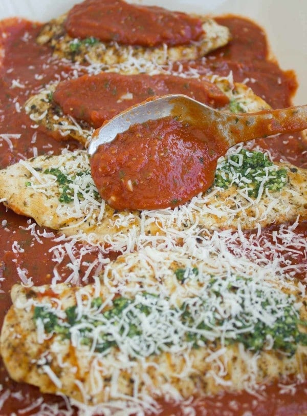 parmesan cheese tops the pesto and more marinara covers the chicken