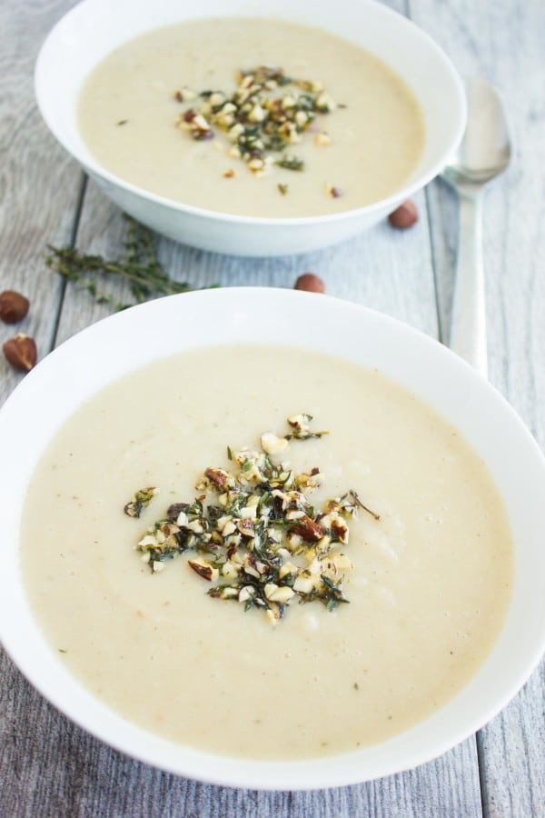 Cauliflower Hazelnut Pear Soup garnished with a crunchy hazelnut topping, served in 2 bowls with some fresh thyme and hazelnuts as decoration