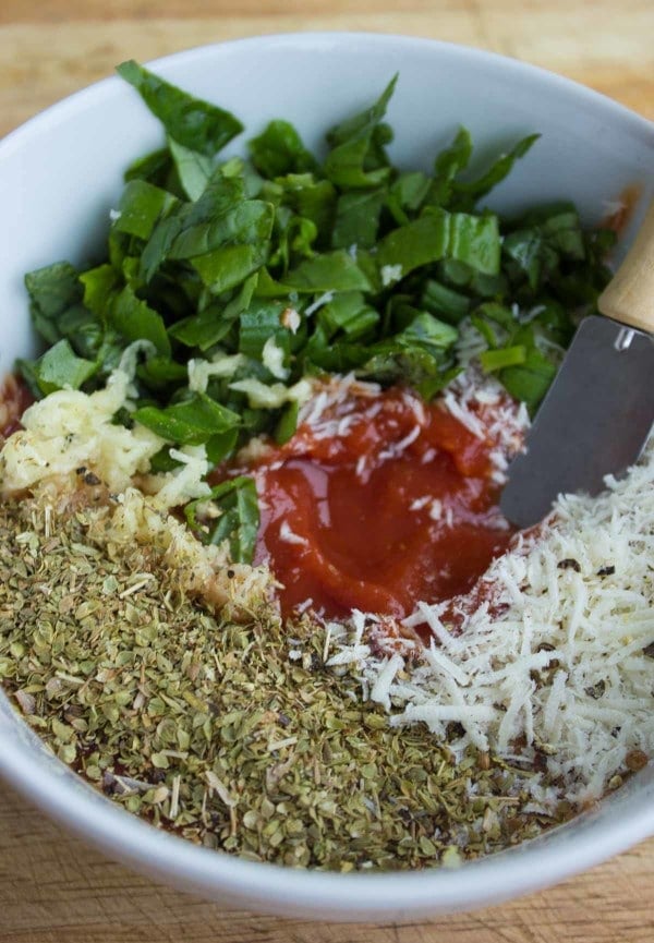 Close up of all ingredients for the pizza sauce: crushed tomatoes, basil, parmesan, garlic, oregano