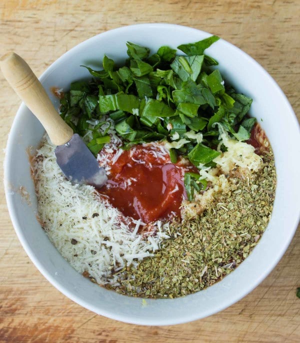 Pizza Sauce ingredients in a small bowl: curshed tomatoes, oregano, basil, garlic, parmesan cheese