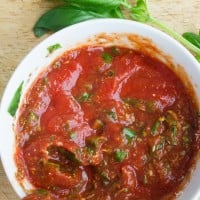 A bowl of pizza sauce recie with a spoon showing he texture