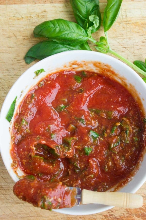 A bowl of pizza sauce recie with a spoon showing he texture