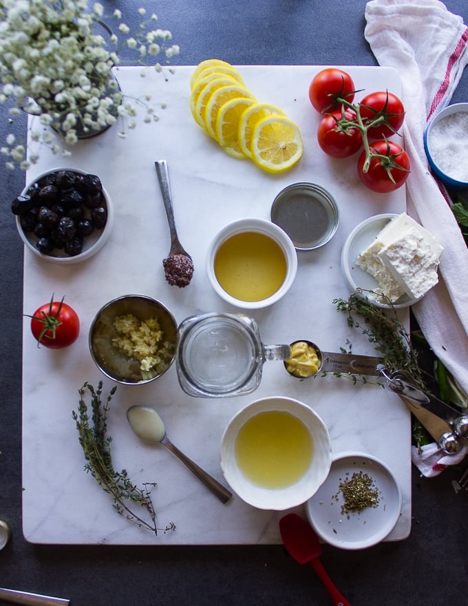 Ingredients used in greek salad dressing including lemon juice, vinegat, garlic, honey, olive oil, mustard, feta cheese and oregano