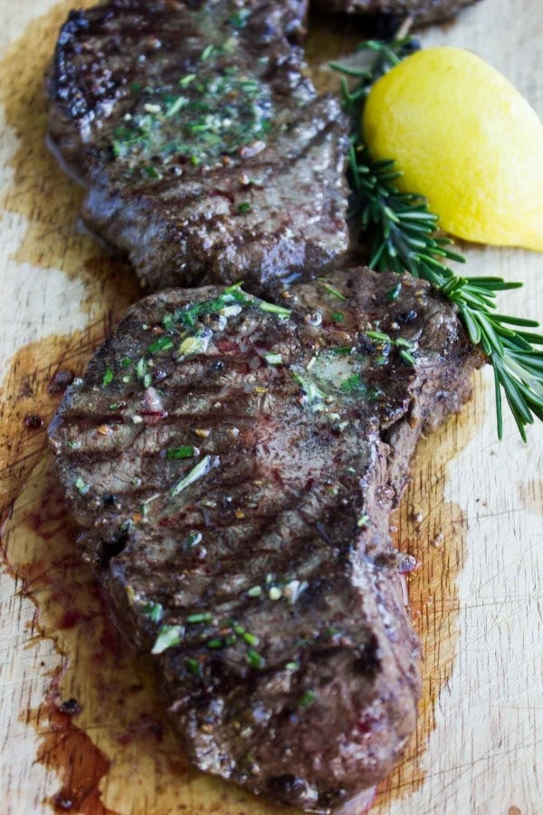 Grilled Steaks smothered with Rosemary Lemon Butter served on a rustic wooden chopping board