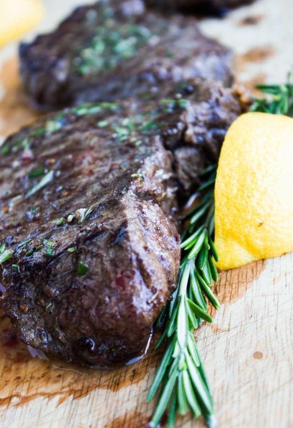 a perfectly Grilled Steak smothered with Rosemary Lemon Butter on a chopping board