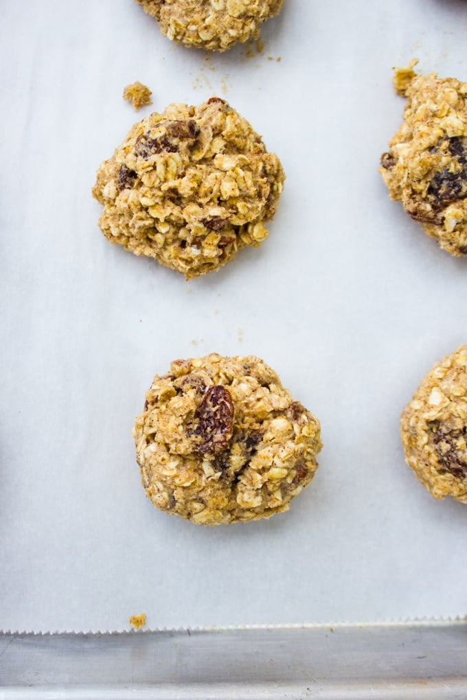 scooped out cookie batters balls into a baking sheet ready to bake into healthy oatmeal raisin cookies 