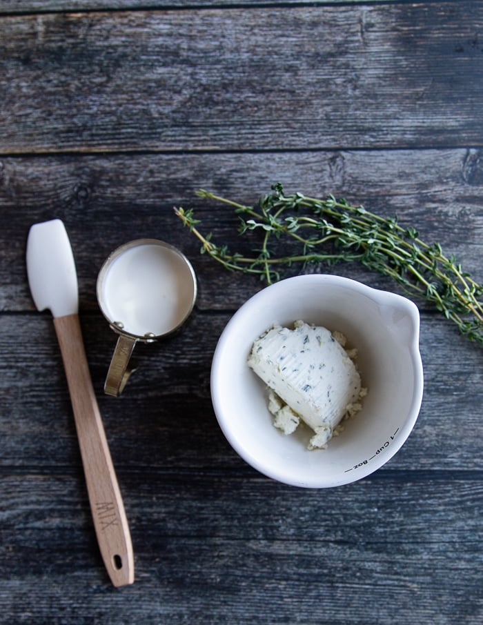 white pizza sauce ingredeints inclusing a bowl of cream cheese, some herbs, salt and a small jar of heavy cream