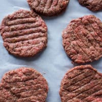 Shaped burger patties on a parchment paper ready to be cooked