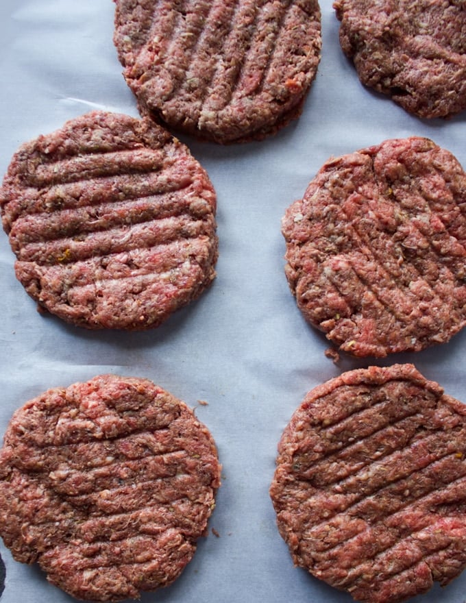 Shaped burger patties on a parchment paper ready to be cooked