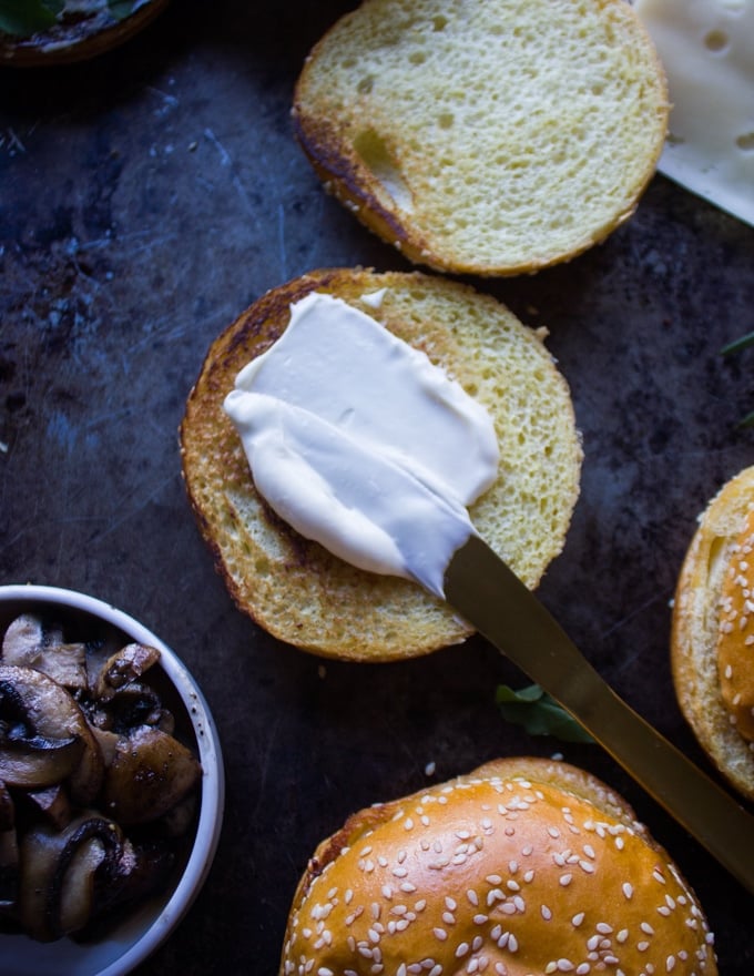 A knife spreading some mayo over the toasted bread