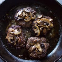 Mushrooms placed over the cooked burgers