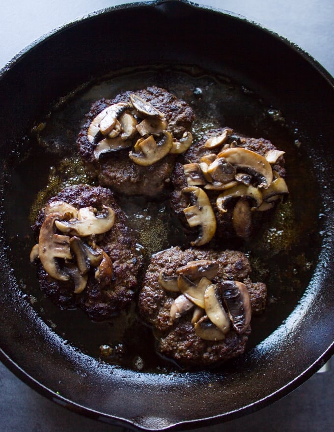 Mushrooms placed over the cooked burgers