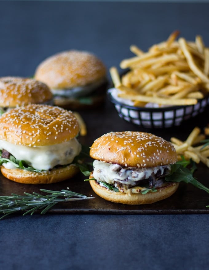 A set of four mushroom burgers on a baking sheet with a plate of fries ready to serve