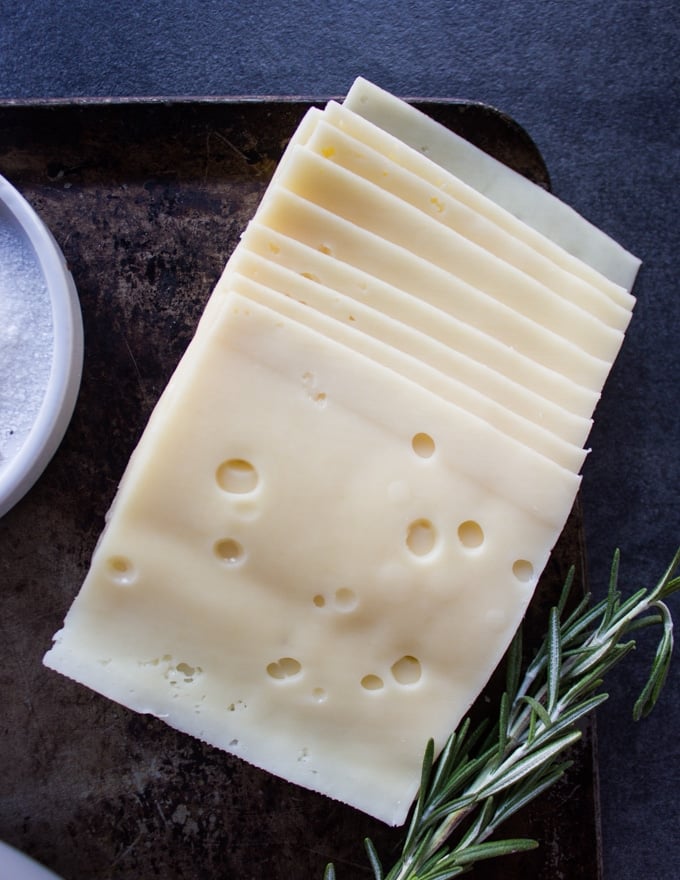 Slices of Swiss Cheese on a board stacked up