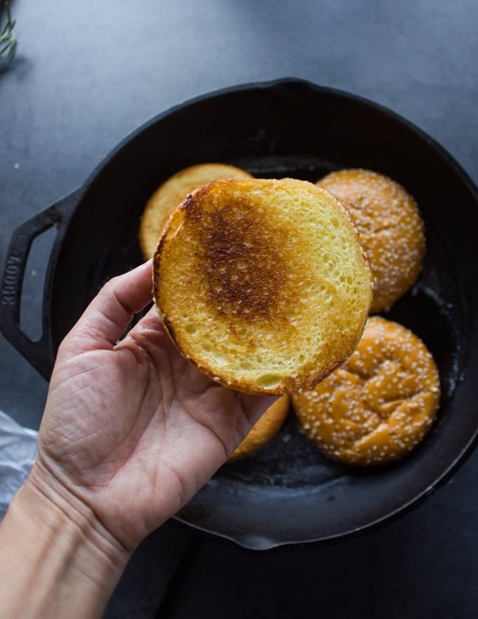 A hand holding the toasted brioche bun showing the golden crust