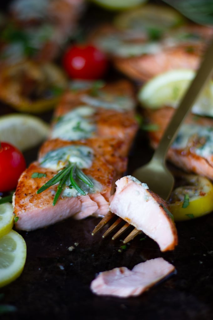 A fork breaking a piece of seared salmon showing how succulent the fish is on the inside.  