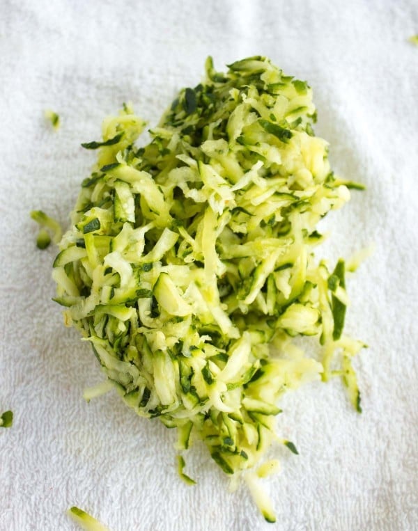 shredded zucchini placed on a sheet of paper kitchen towel to squeeze out moisture