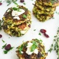 Zucchini Feta Cranberry Fritters served on a white tabletop sprinkled with chopped herbs and cranberries