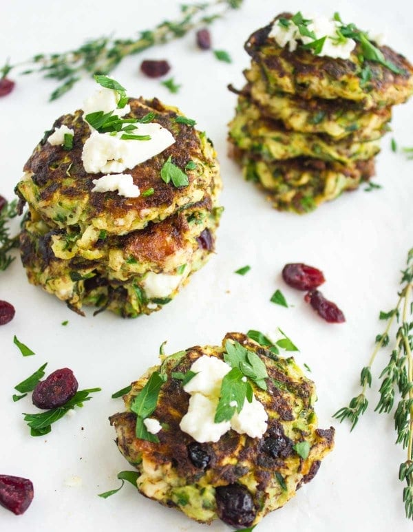 Zucchini Fritters with Cranberries and Feta stacked on top of each other on a white tabletop