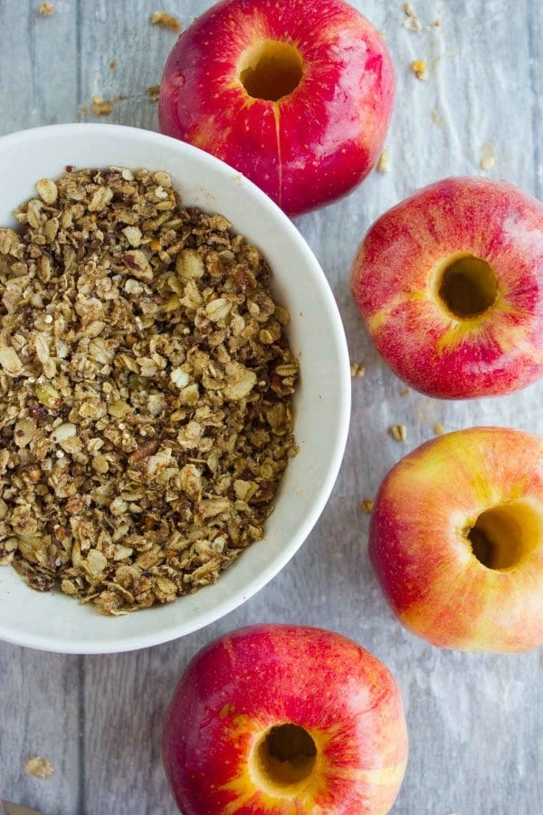 a bowl of granola with whole cored apples on the side