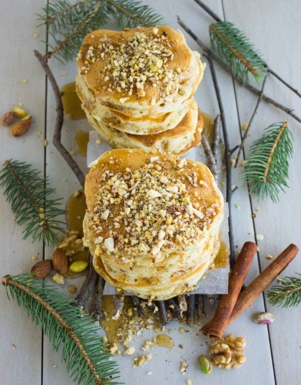 two stacks of Baklava Pancakes with Maple Syrup surrounded by cinnamon sticks and spruce twigs