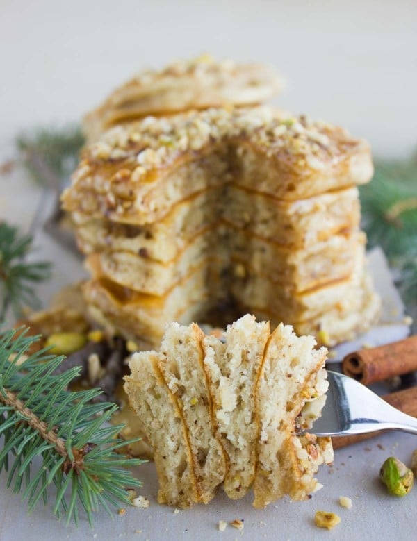 a fork full of Baklava Pancakes with Maple Syrup in front of a stack of pancakes