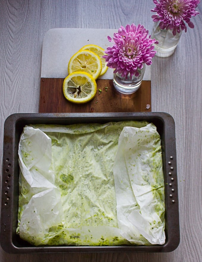 A frozen pan of basil pesto out of the freezer wrapped in parchment paper