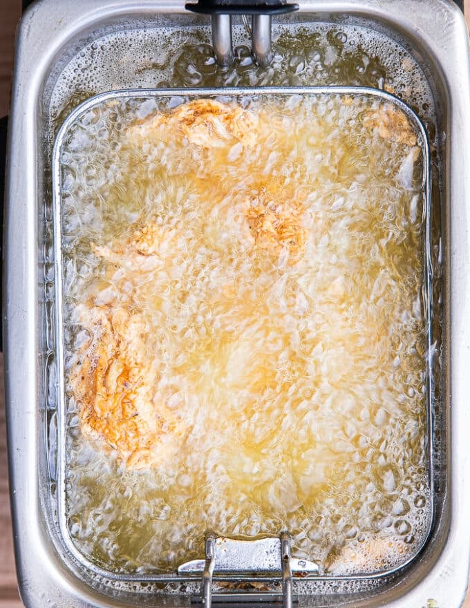 Chicken fingers submerged in hot oil and frying 