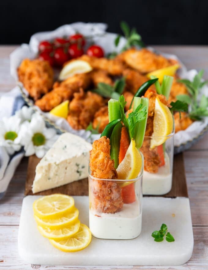 chicken fingers served in a cup with blue cheese dressing and celery and carrots and lemon wedges