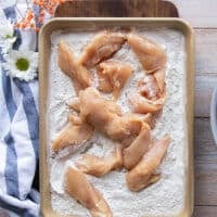 Chicken breasts cut up into strips and placed over the flavored flour sheet.