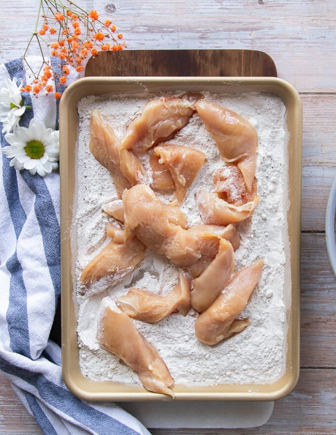 Chicken breasts cut up into strips and placed over the flavored flour sheet.
