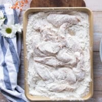 Chicken fingers entirely coated in flour for the first coating.