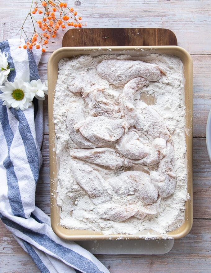 Chicken fingers entirely coated in flour for the first coating.