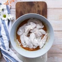 chicken fingers coated in flour added to the bowl of wet coating