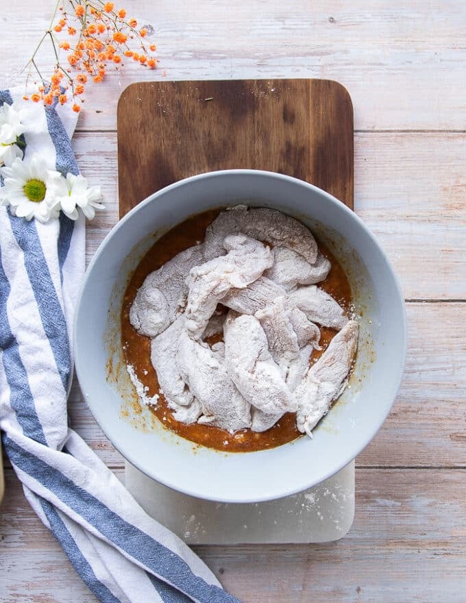 chicken fingers coated in flour added to the bowl of wet coating