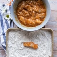 A chicken finger removed from the wet ingredients and placed in the flour for the second coating