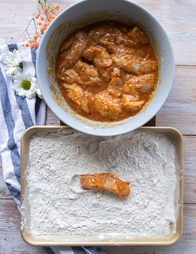 A chicken finger removed from the wet ingredients and placed in the flour for the second coating 