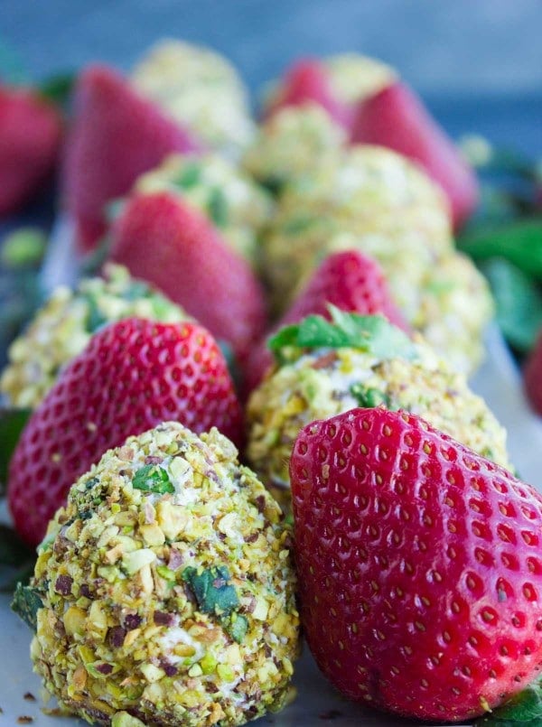 Close-up of Goat Cheese Pistachio Coated Strawberries and fresh strawberries lined up on a white rectangular plate.