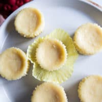 cooled cheesecakes on a plate and a hand peeling off the baking ppers