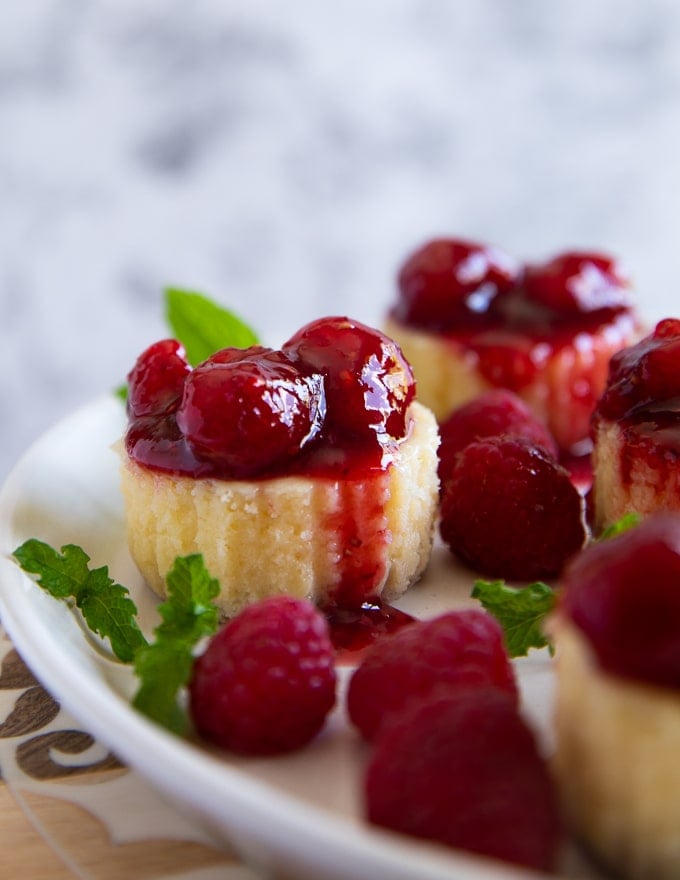 one mini cheesecake with raspberry sauce close up showing the dense texture