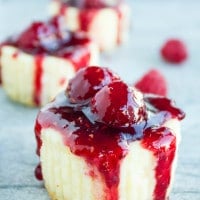 side view of Mini Raspberry Cheesecakes with raspberry sauce