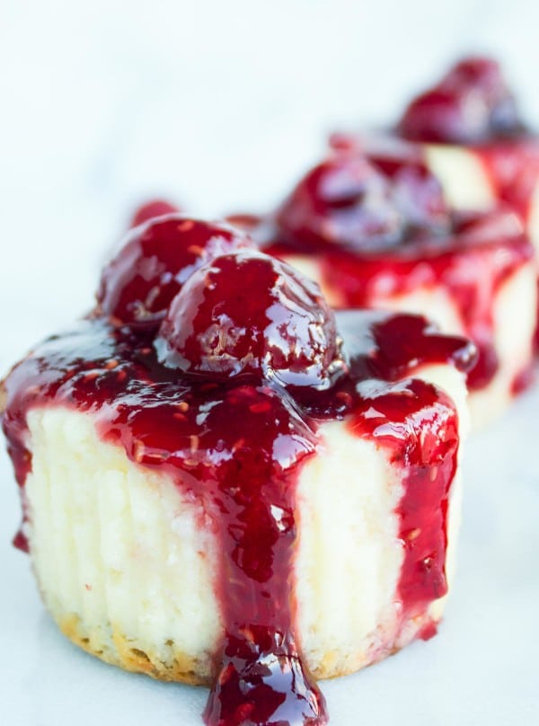 side view of Mini Cheesecakes topped with raspberry sauce and fresh raspberries