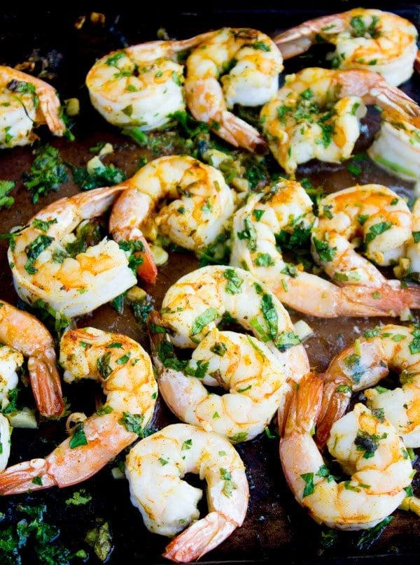broiled, herb and oil coated shrimp on a black baking tray