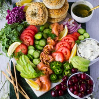 A fully arranged platter with the bagels, veggies, fruits, the sauces and ready to eat