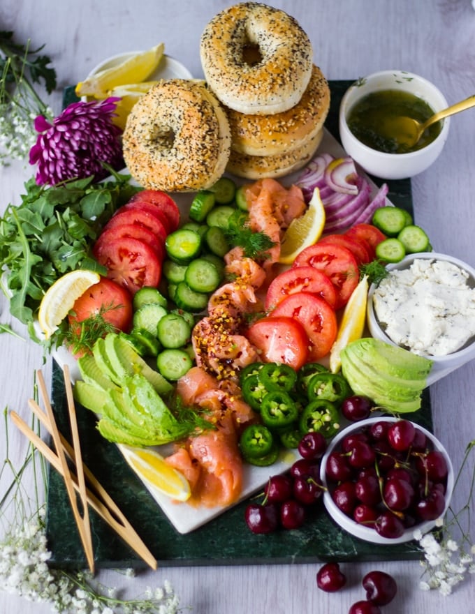 A fully arranged platter with the bagels, veggies, fruits, the sauces and ready to eat