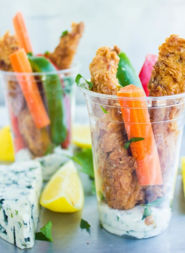 Spicy Fried Chicken Fingers arranged in plastic cup with veggie sticks