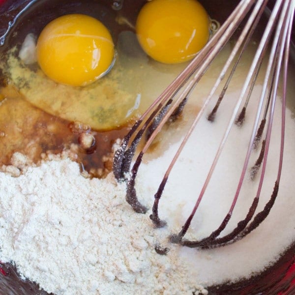 all ingredients for gluten free brownies recipe in a bowl with a whisk 