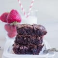 a stack of gluten free brownies recipe on a plate with strawberries and milk